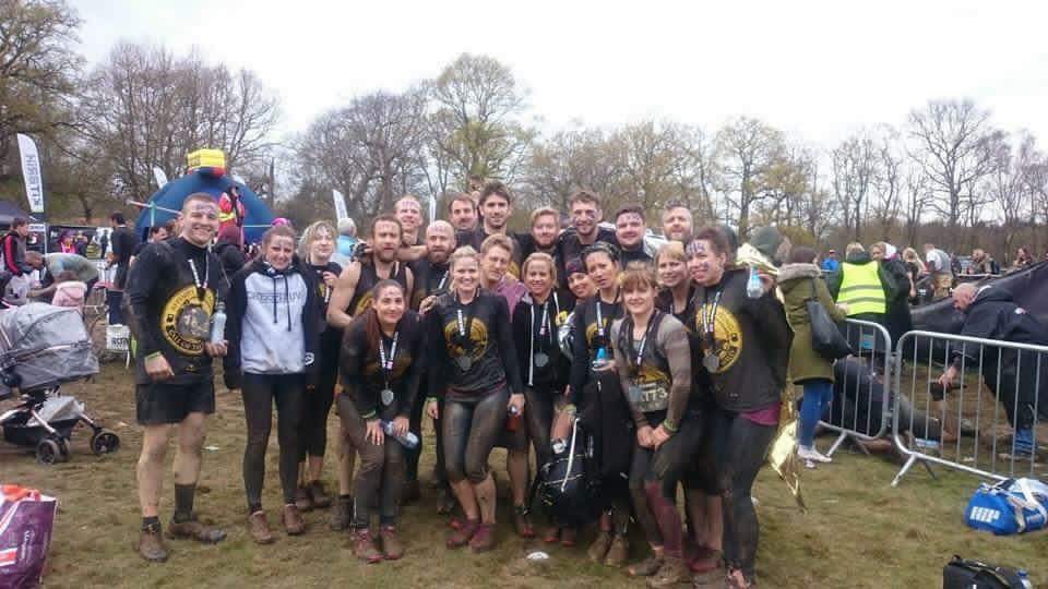 A group of people following a muddy challenge posing for the camera.