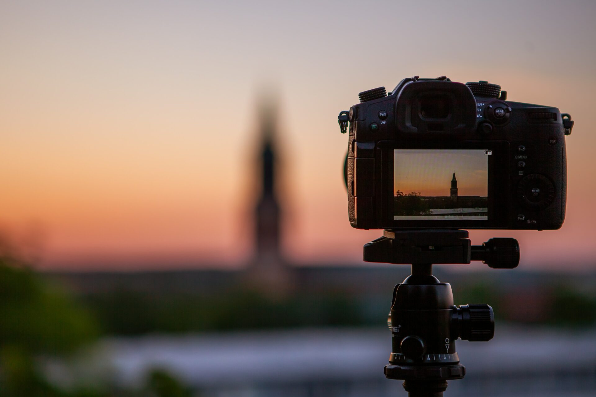 Camera taking a photo of a sunset and tall building
