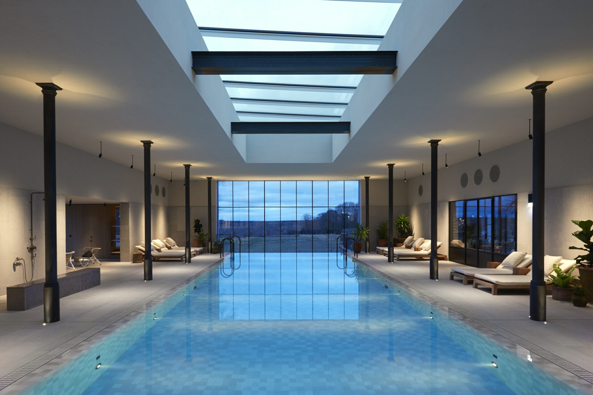 Indoor swimming pool in a hotel with sun loungers and a roof lantern
